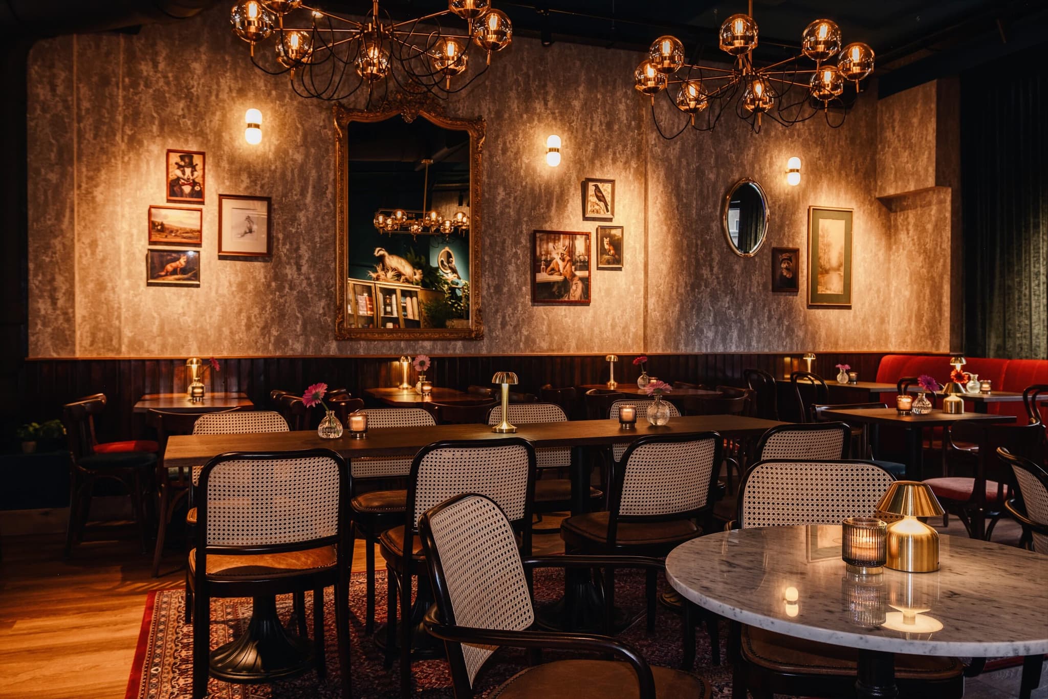 The candlelit dining room at The Fat Fox in Rotterdam — green velvet, cane chairs, brass chandeliers and Victorian portraits